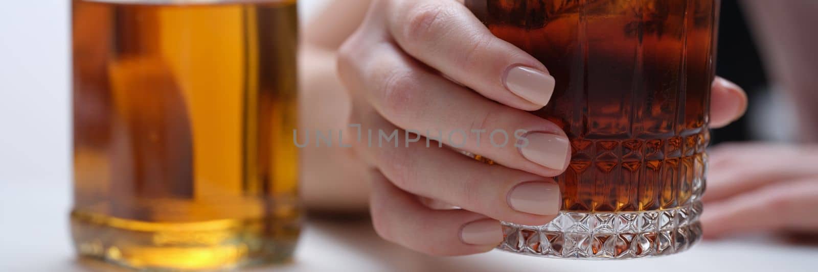 Woman hand holds glass of whiskey or cognac with bottle. Woman suffering from alcohol addiction and depressed woman drinking hard alcohol concept