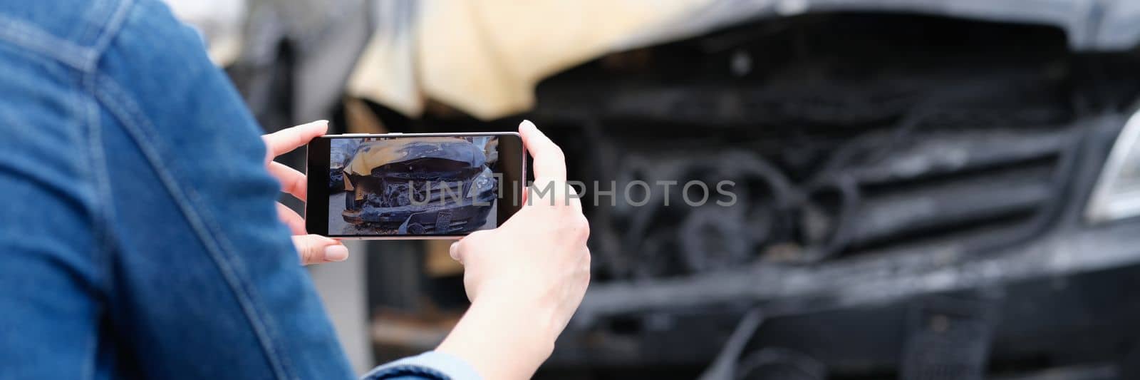 Woman insurance agent or reporter journalist taking pictures of burnt car by kuprevich
