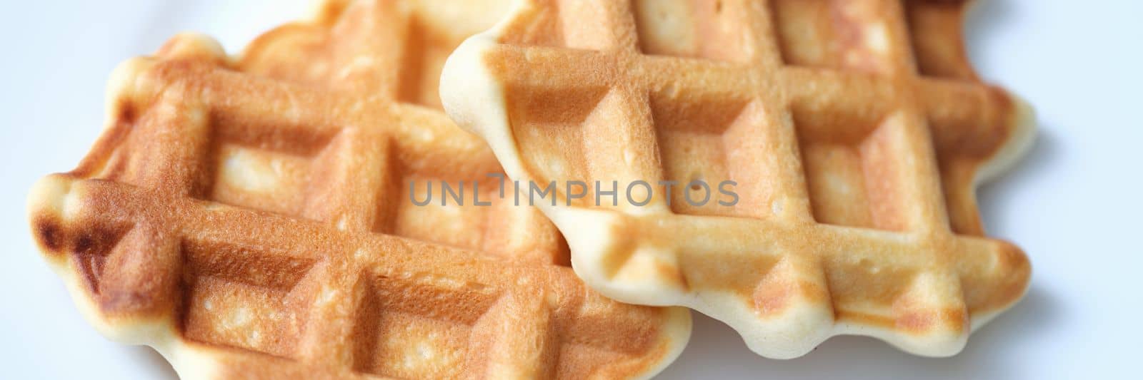 Two freshly baked Belgian waffles on white plate. Recipe dough for Belgian waffles concept