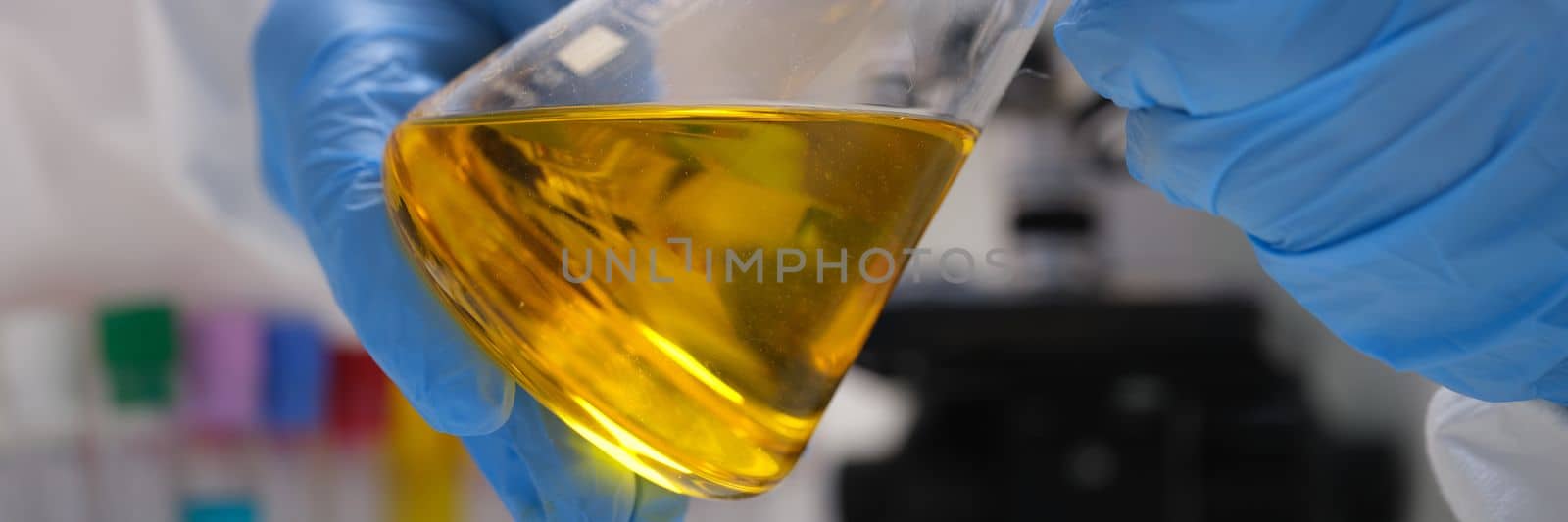 Chemist in gloves holds test tube with yellow oily liquid for research closeup. Laboratory research materials urine or oil toxic and poisonous concept