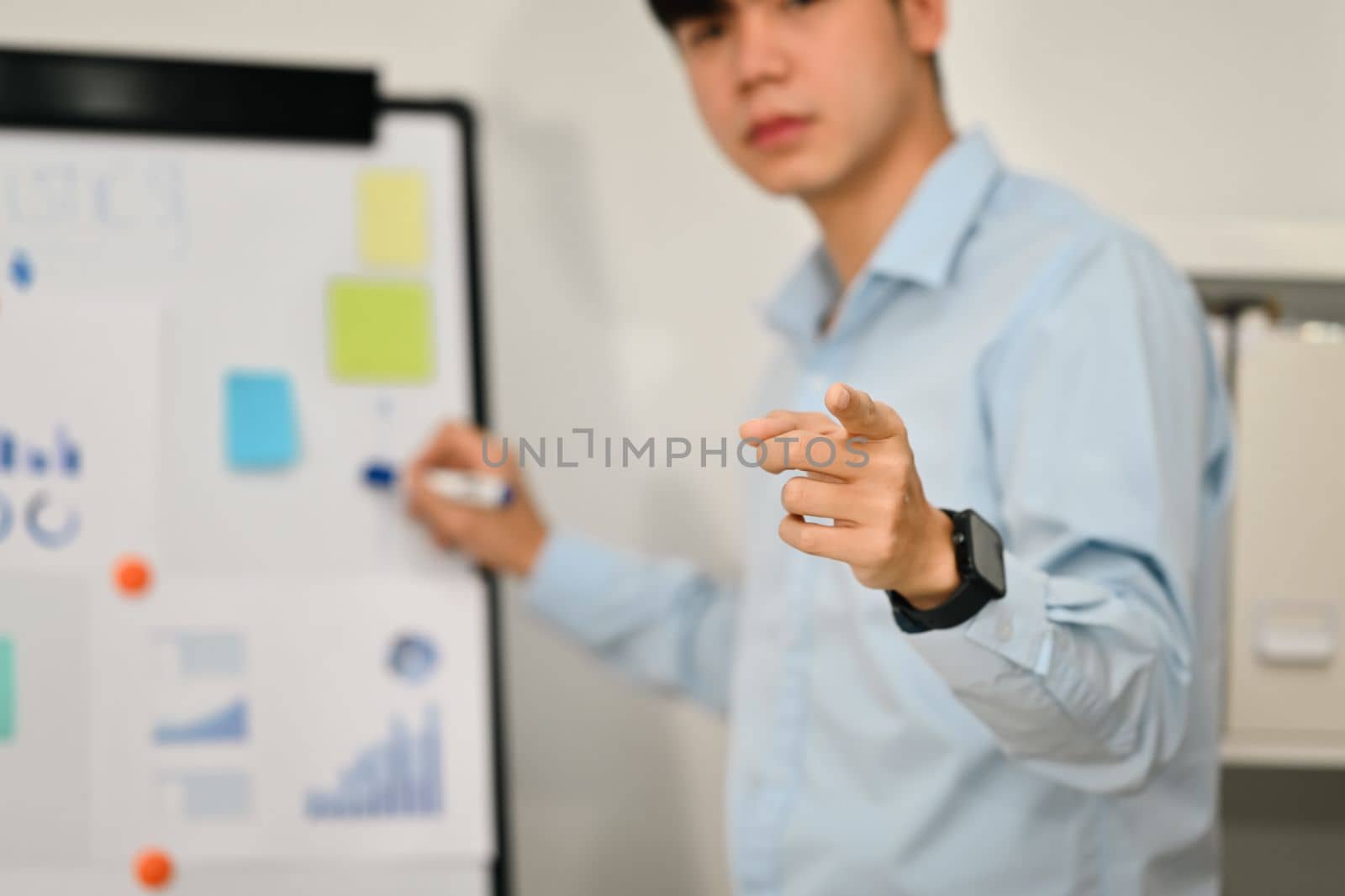 Selective focus, businessman pointing fingers at camera while presenting business data on whiteboard by prathanchorruangsak