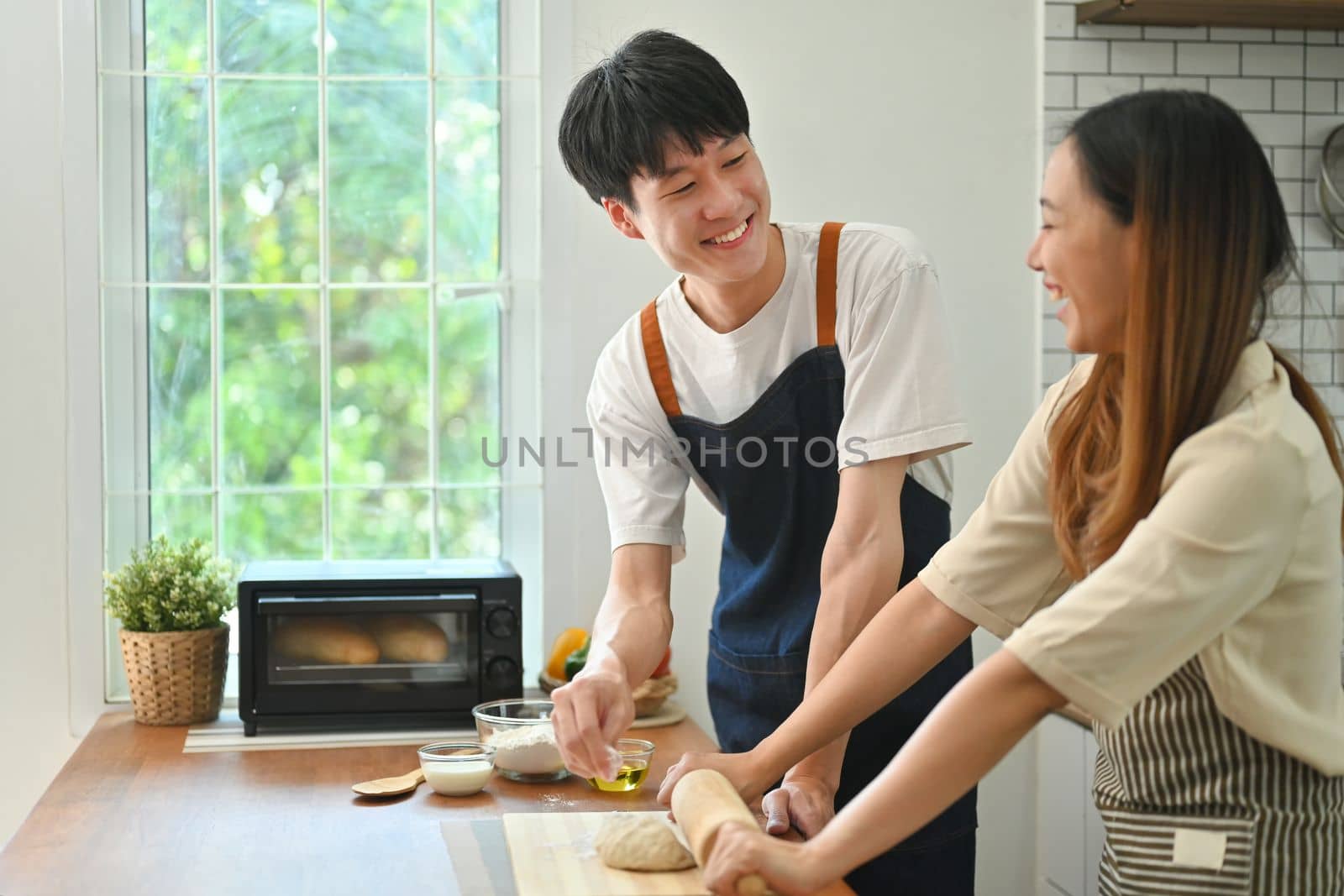 Romantic asian couple preparing homemade pastry on wooden table in kitchen. Love, relationship, people and family.