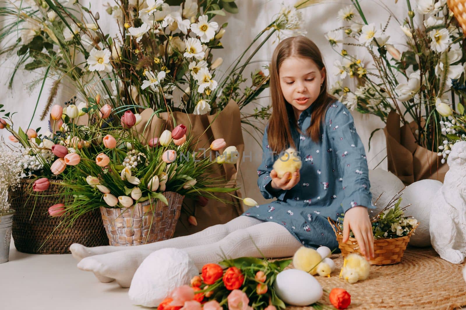 Two girls in a beautiful Easter photo zone with flowers, eggs, chickens and Easter bunnies. Happy Easter holiday