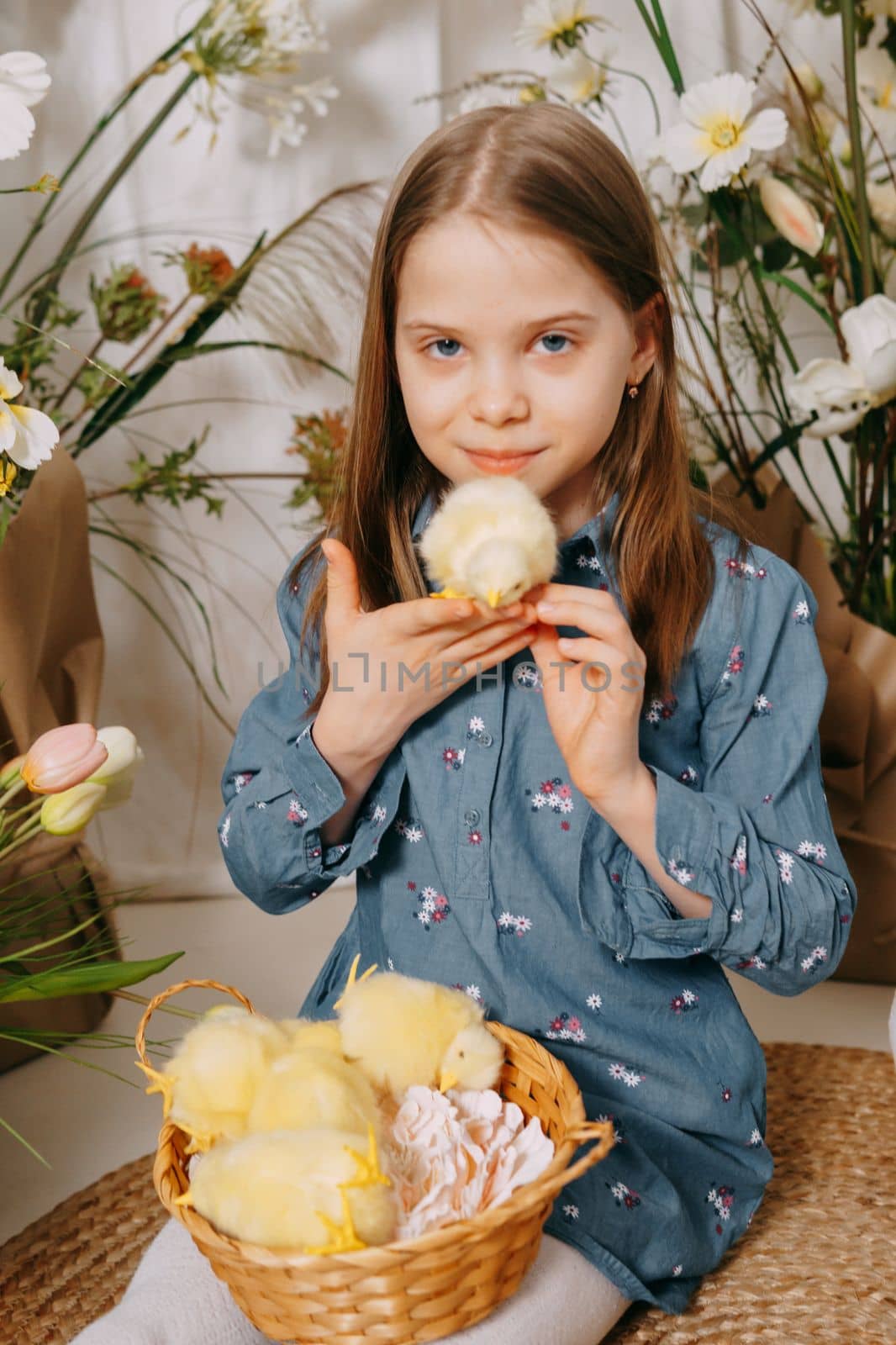 Two girls in a beautiful Easter photo zone with flowers, eggs, chickens and Easter bunnies. Happy Easter holiday