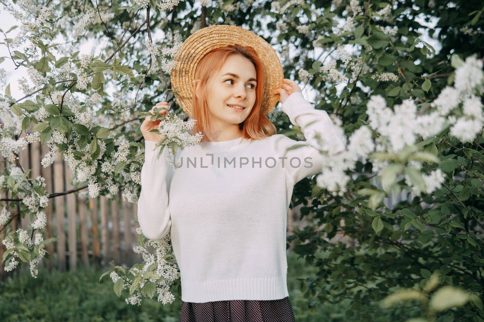Portrait of a woman in a straw hat in a cherry blossom. Free outdoor recreation, spring blooming garden