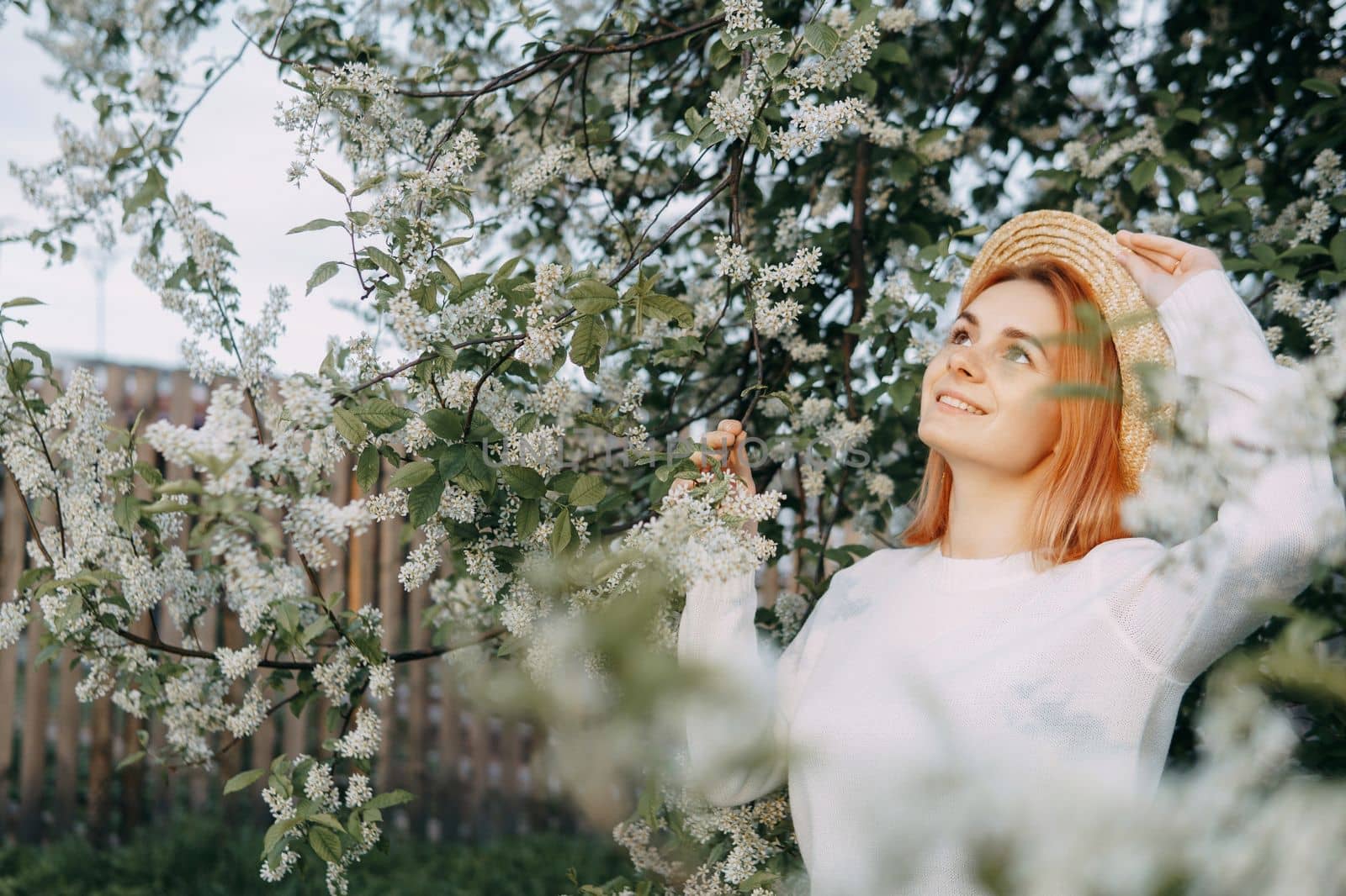 Portrait of a woman in a straw hat in a cherry blossom. Free outdoor recreation, spring blooming garden