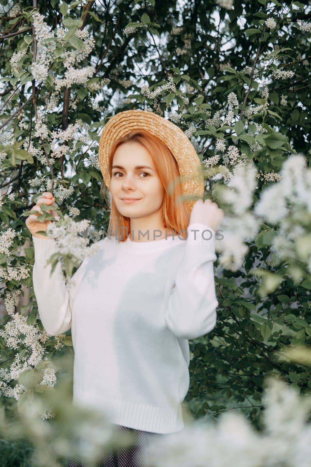 Portrait of a woman in a straw hat in a cherry blossom. Free outdoor recreation, spring blooming garden