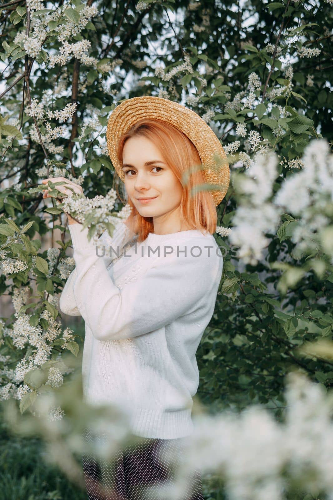 Portrait of a woman in a straw hat in a cherry blossom. Free outdoor recreation, spring blooming garden