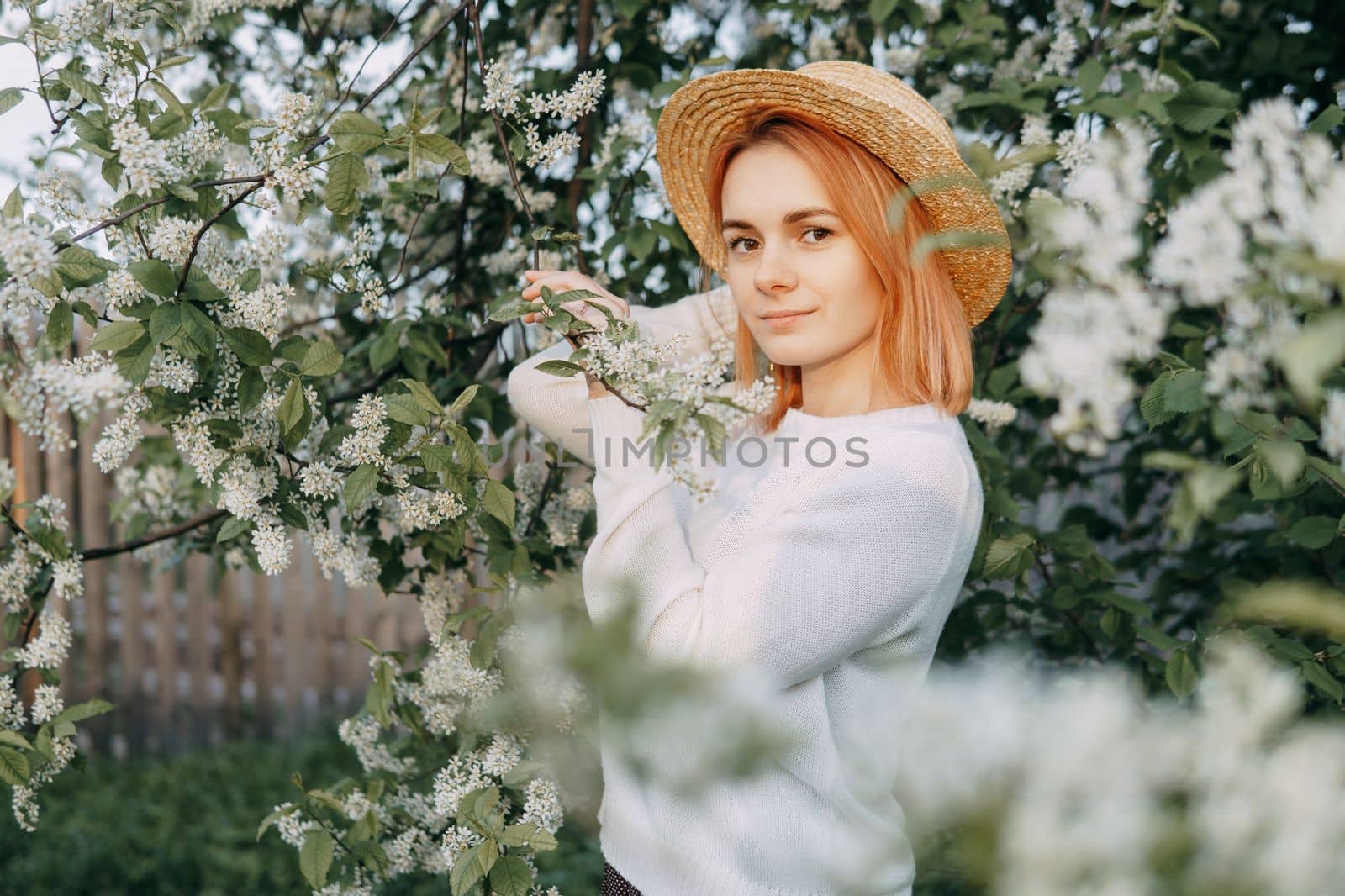 Portrait of a woman in a straw hat in a cherry blossom. Free outdoor recreation, spring blooming garden