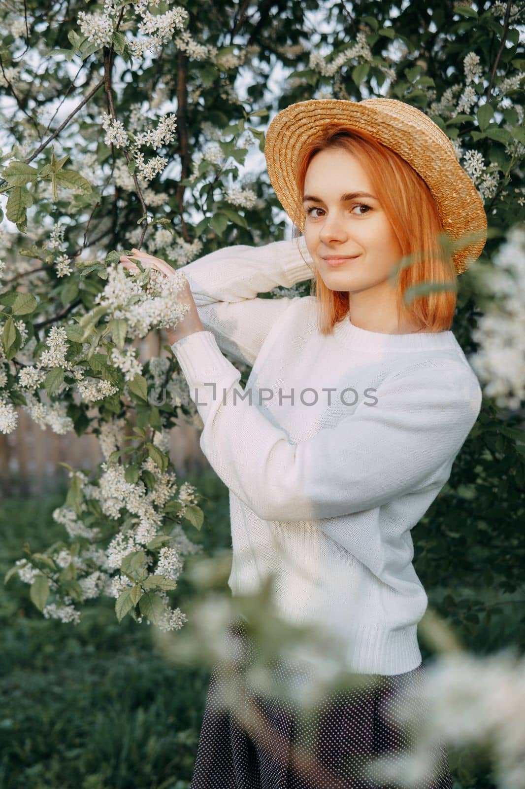 Portrait of a woman in a straw hat in a cherry blossom. Free outdoor recreation, spring blooming garden