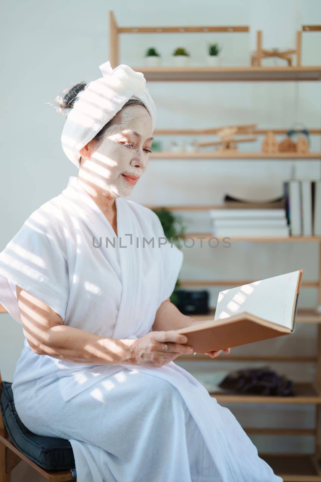 Portrait of elderly woman doing face spa treatment and using notebook. by Manastrong