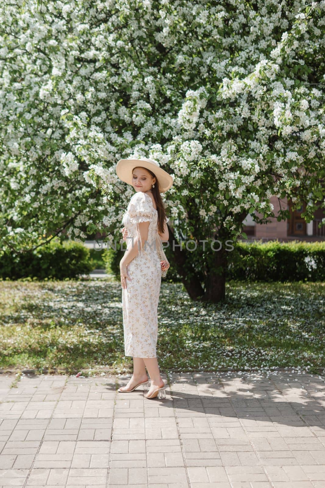 An attractive long-haired woman walks in the spring in the park of blooming apple trees. by Annu1tochka