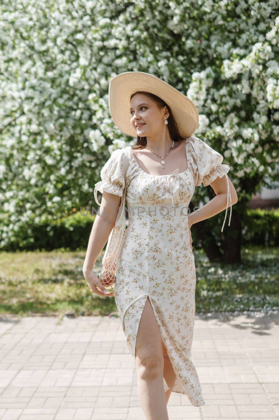 An attractive long-haired woman walks in the spring in the park of blooming apple trees. Spring portrait of a woman