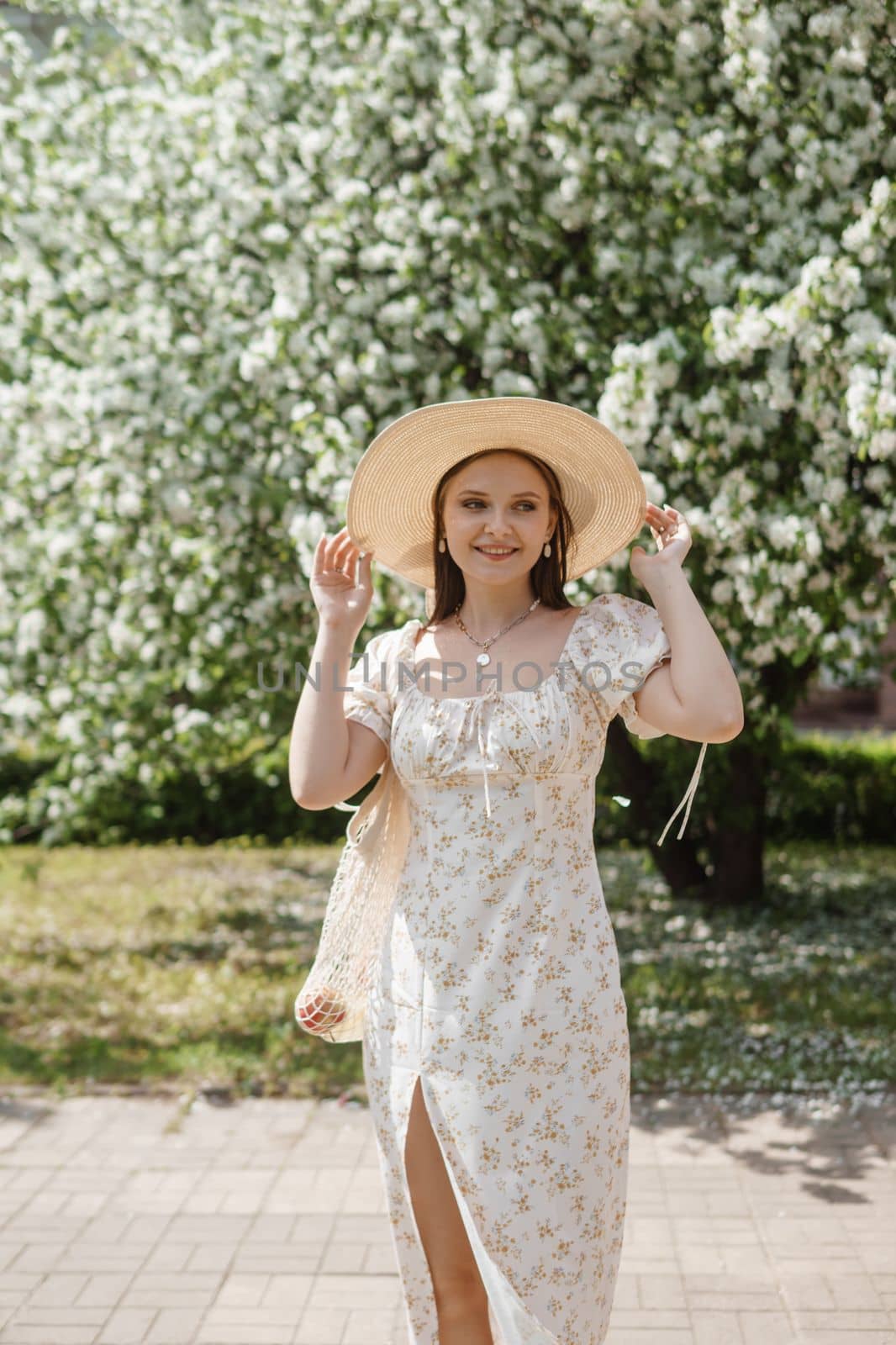 An attractive long-haired woman walks in the spring in the park of blooming apple trees. Spring portrait of a woman