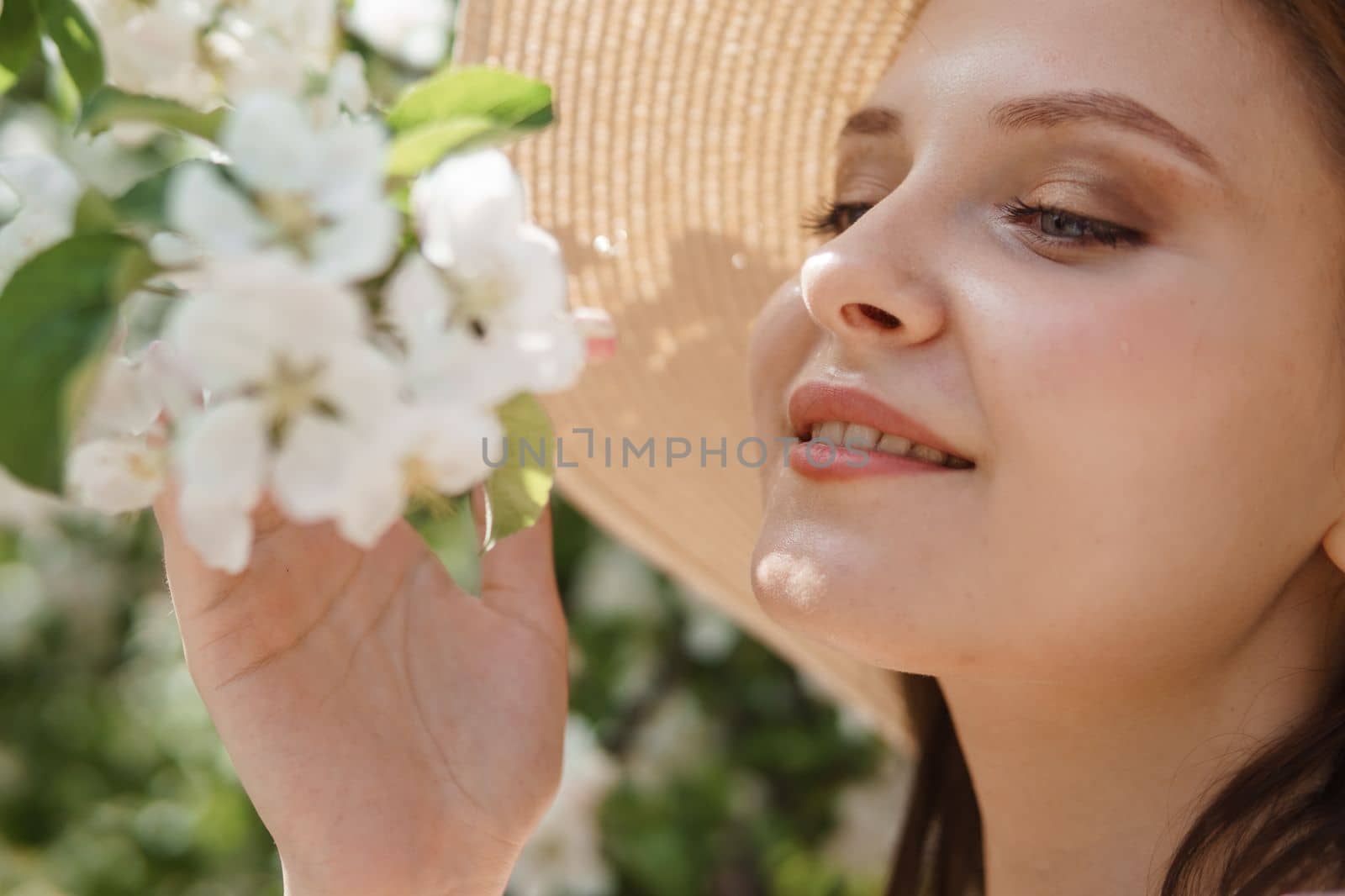 An attractive long-haired woman walks in the spring in the park of blooming apple trees. Spring portrait of a woman