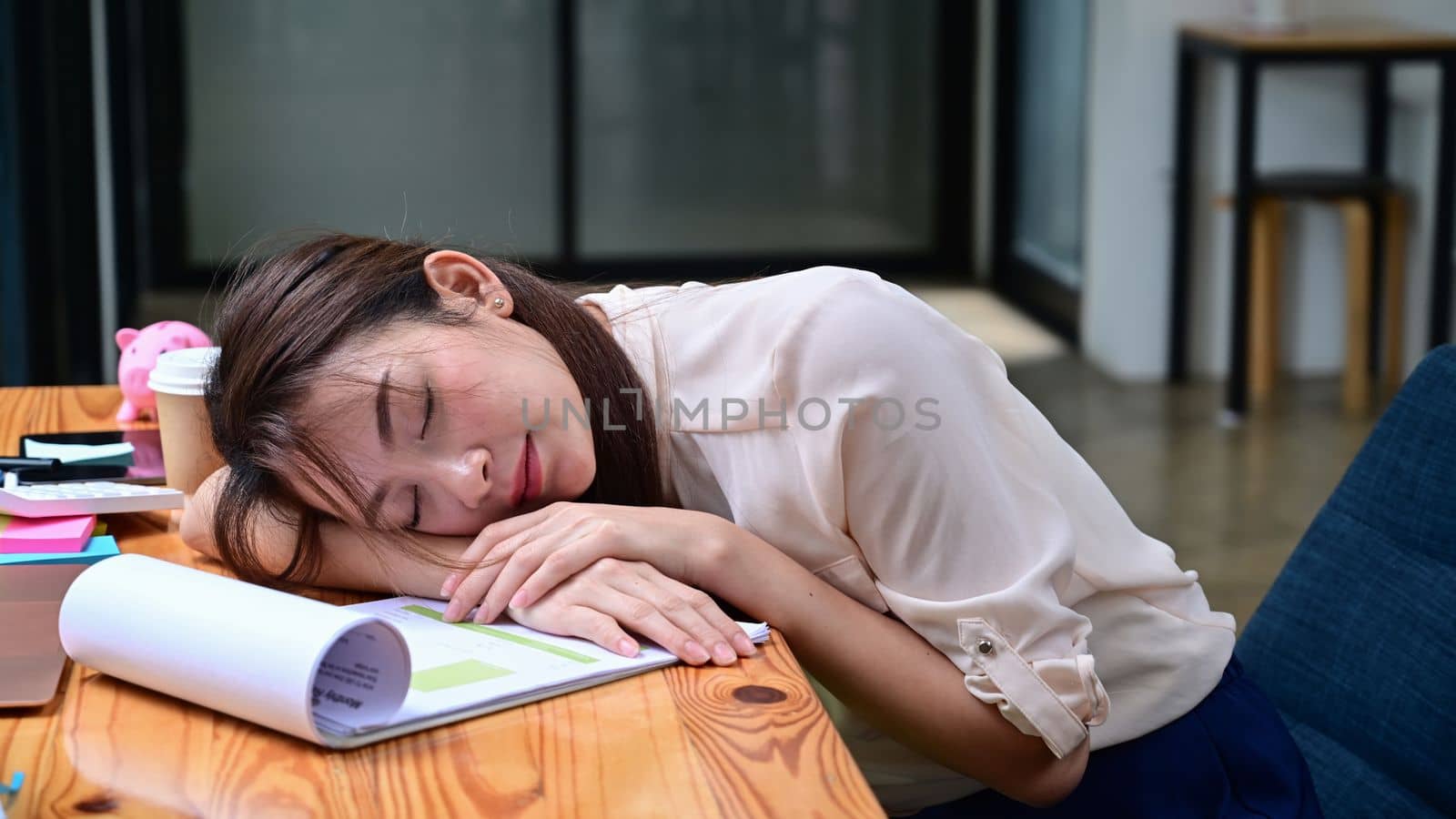 Tired businesswoman sleeping on office desk in front of laptop computer. by prathanchorruangsak