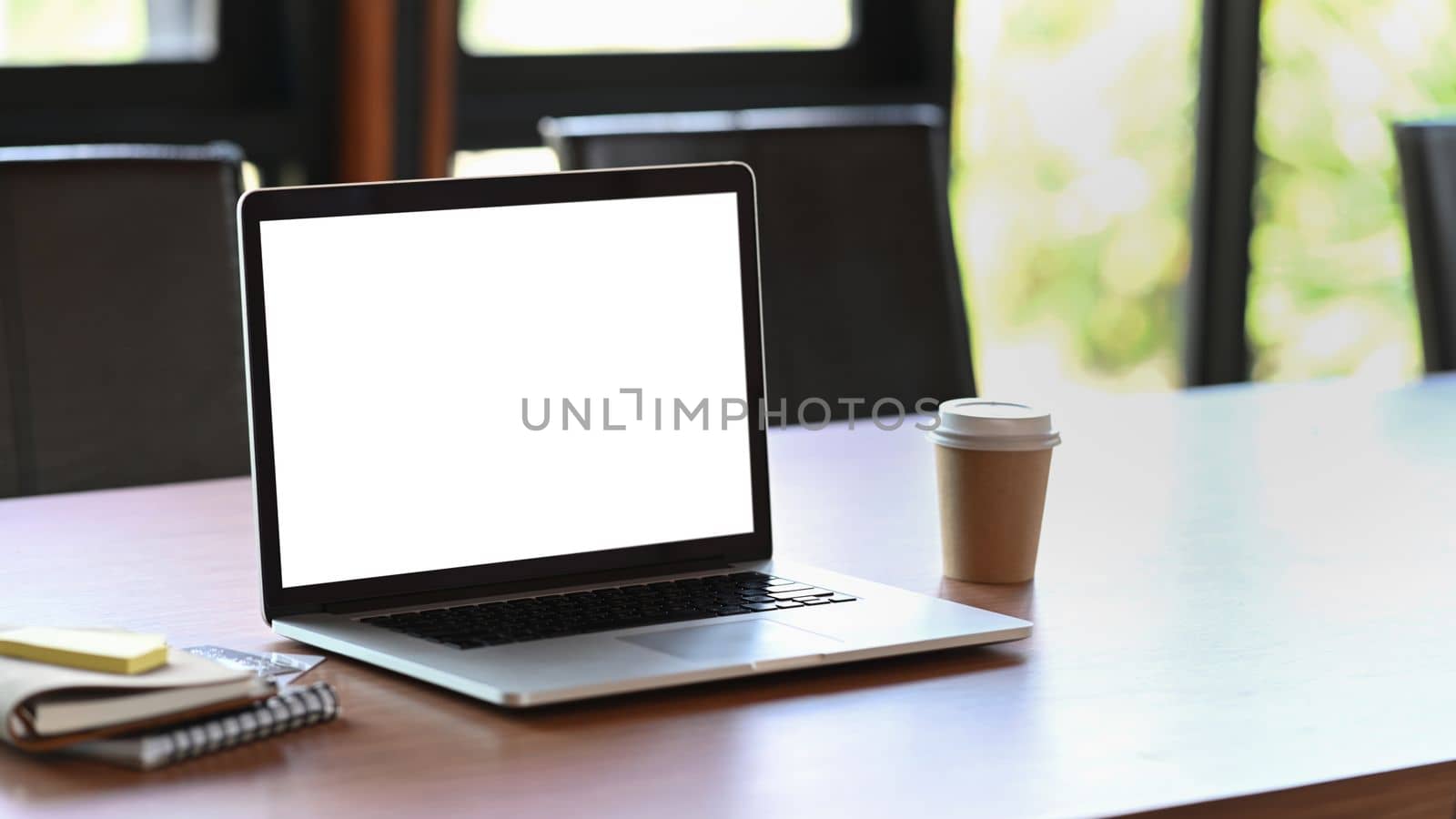 Mock up computer laptop, coffee cup and books on wooden table.