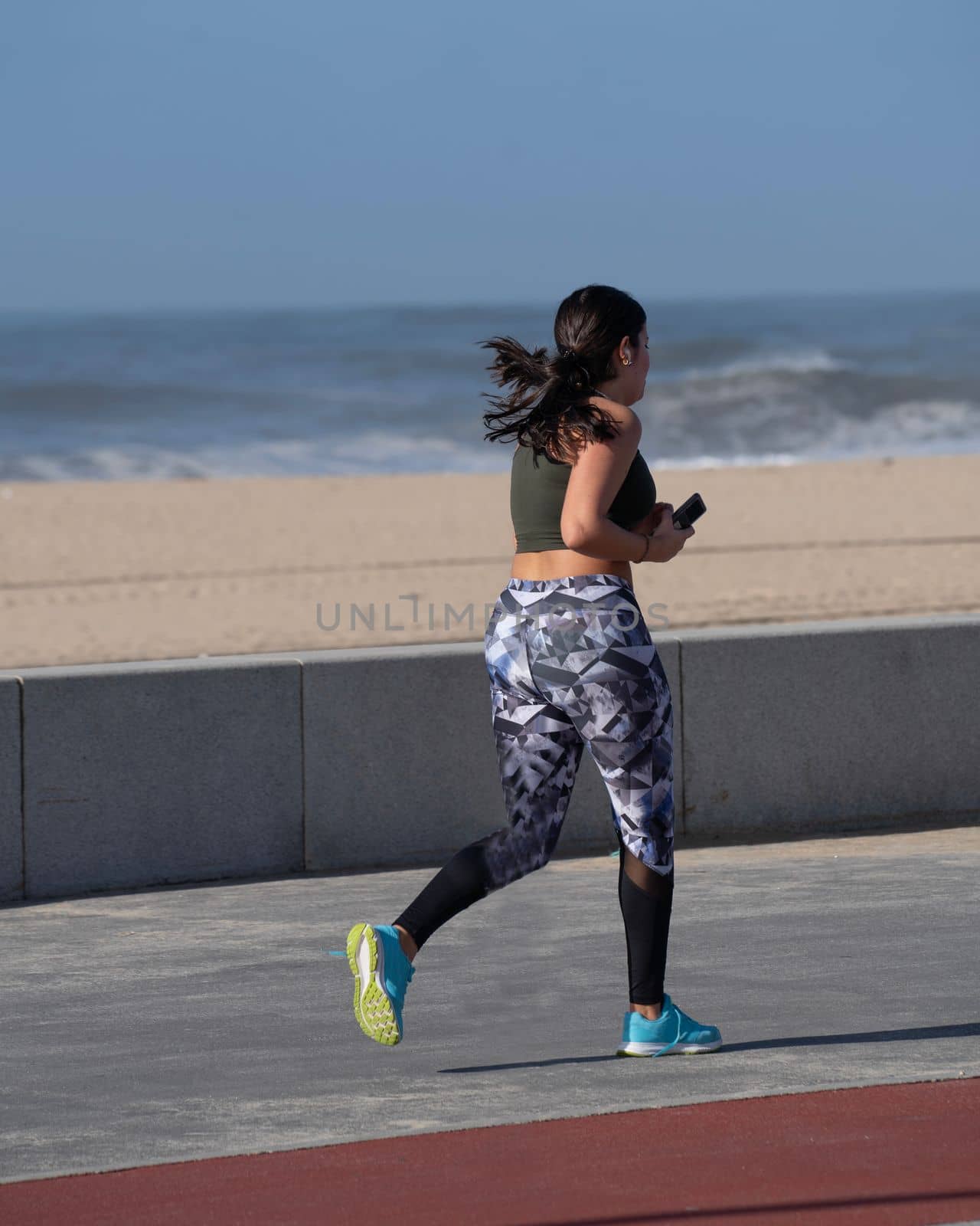 Portrait of young american girl in headphones running on promenade.