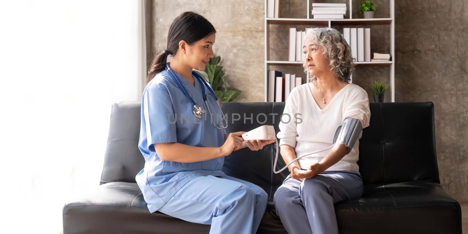 Senior woman having her blood pressure measured in a nursing home by her caregiver. Nurse measuring blood pressure of a senior woman.