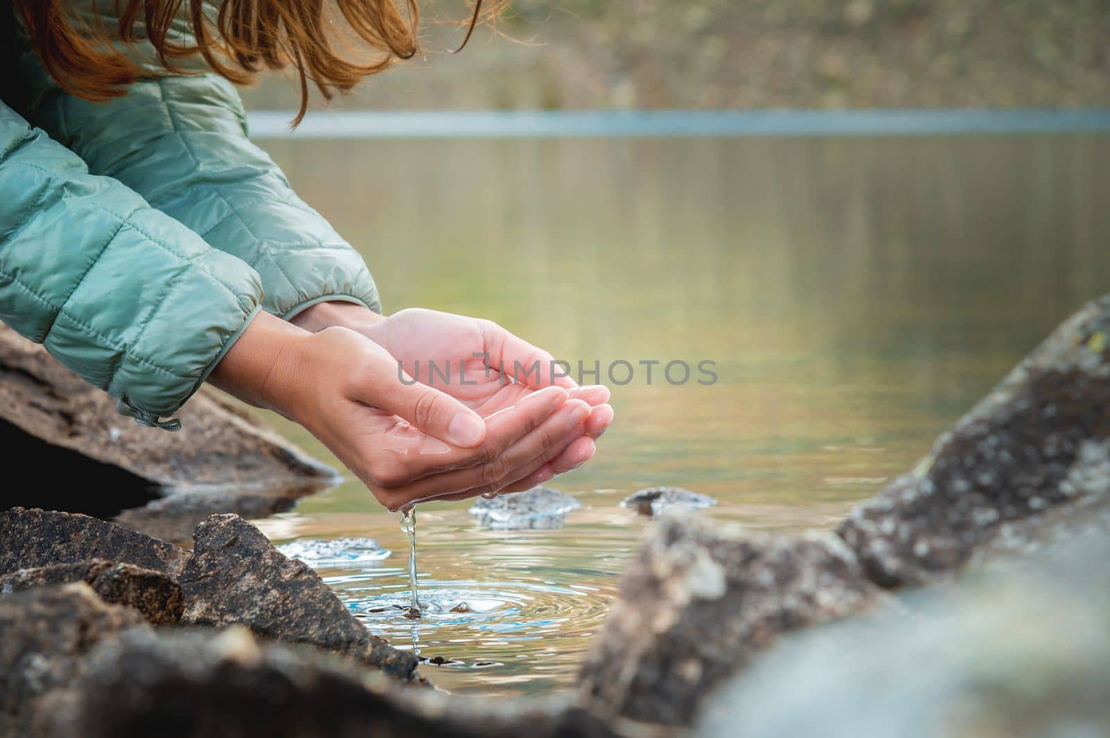 hand touches the water in the pond. dripping liquid from palms. Female hands with splashes of water from a mountain lake, close-up by yanik88