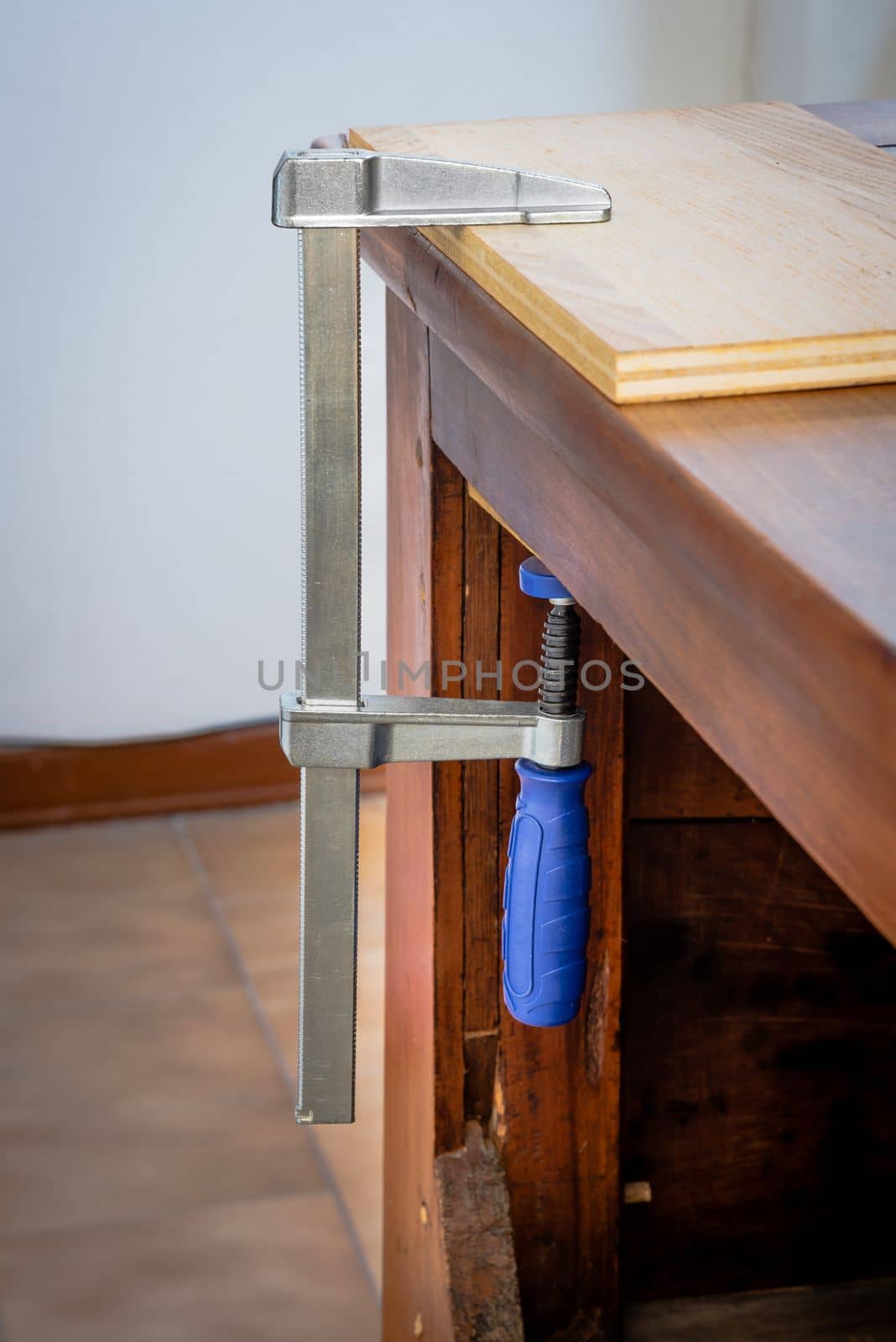 Restoration of an antique French wooden furniture using wood clamps to attach different parts of it