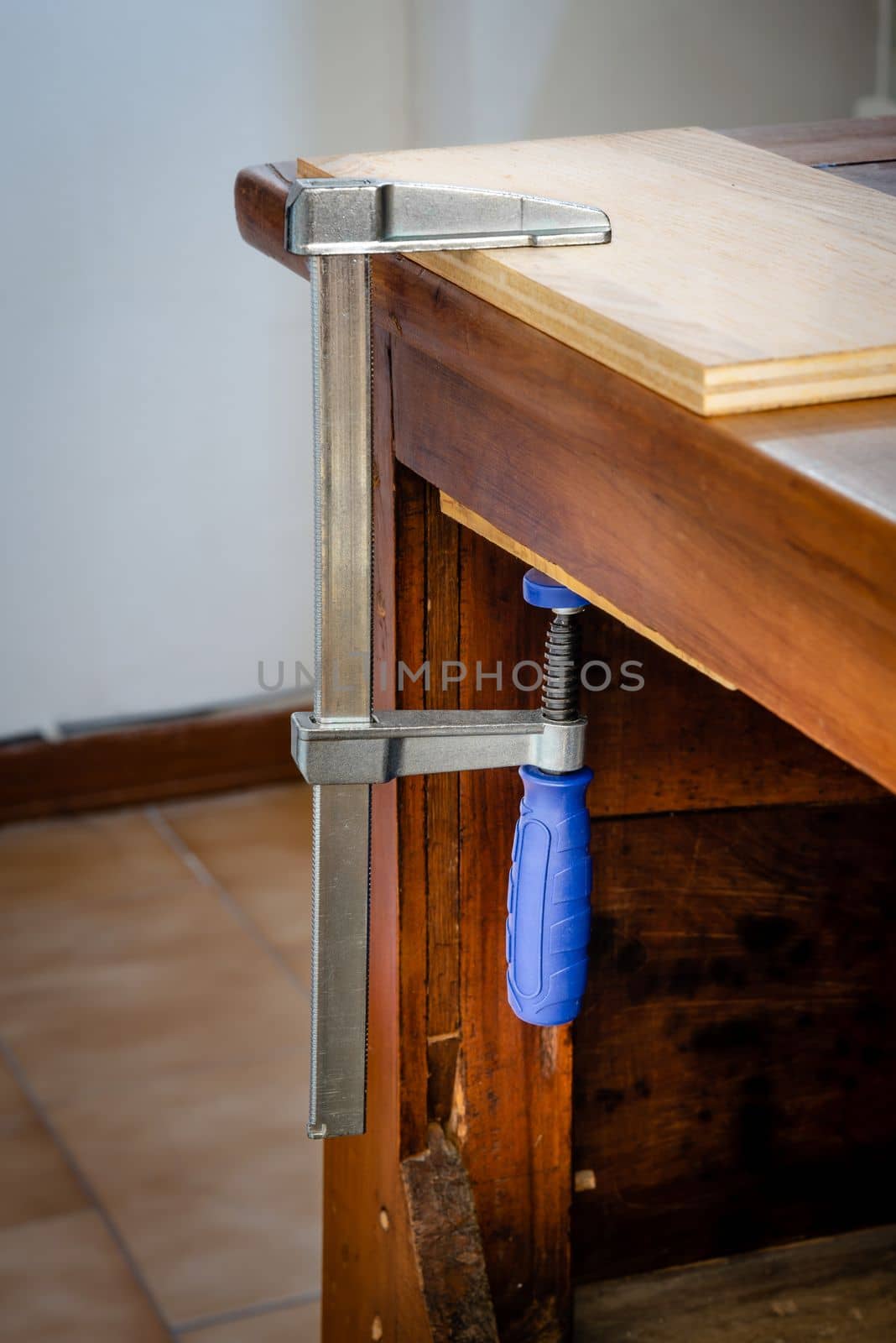 Restoration of an antique French wooden furniture using wood clamps to attach different parts of it