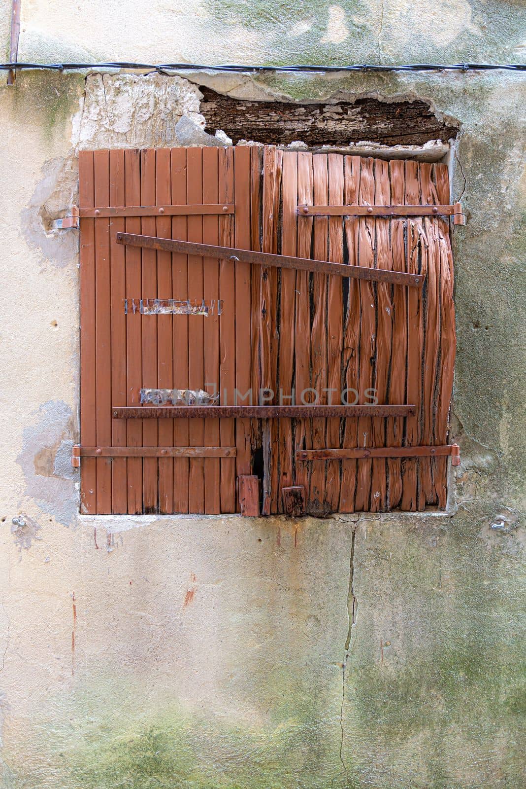 Old broken wooden shutter and an old concrete wall in the town of Brignoles, Provence, South of France