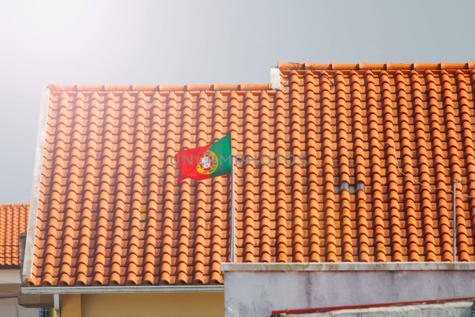portuguese flag on a tiled roof background , summer evening