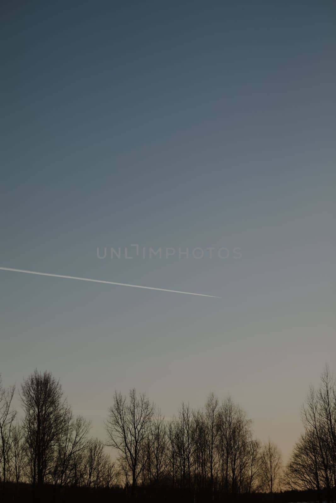 airplane flies in sunset sky and leaving trail. Amazing panoramic sunrise or sunset sky. Gradient color. Sky texture, abstract nature background