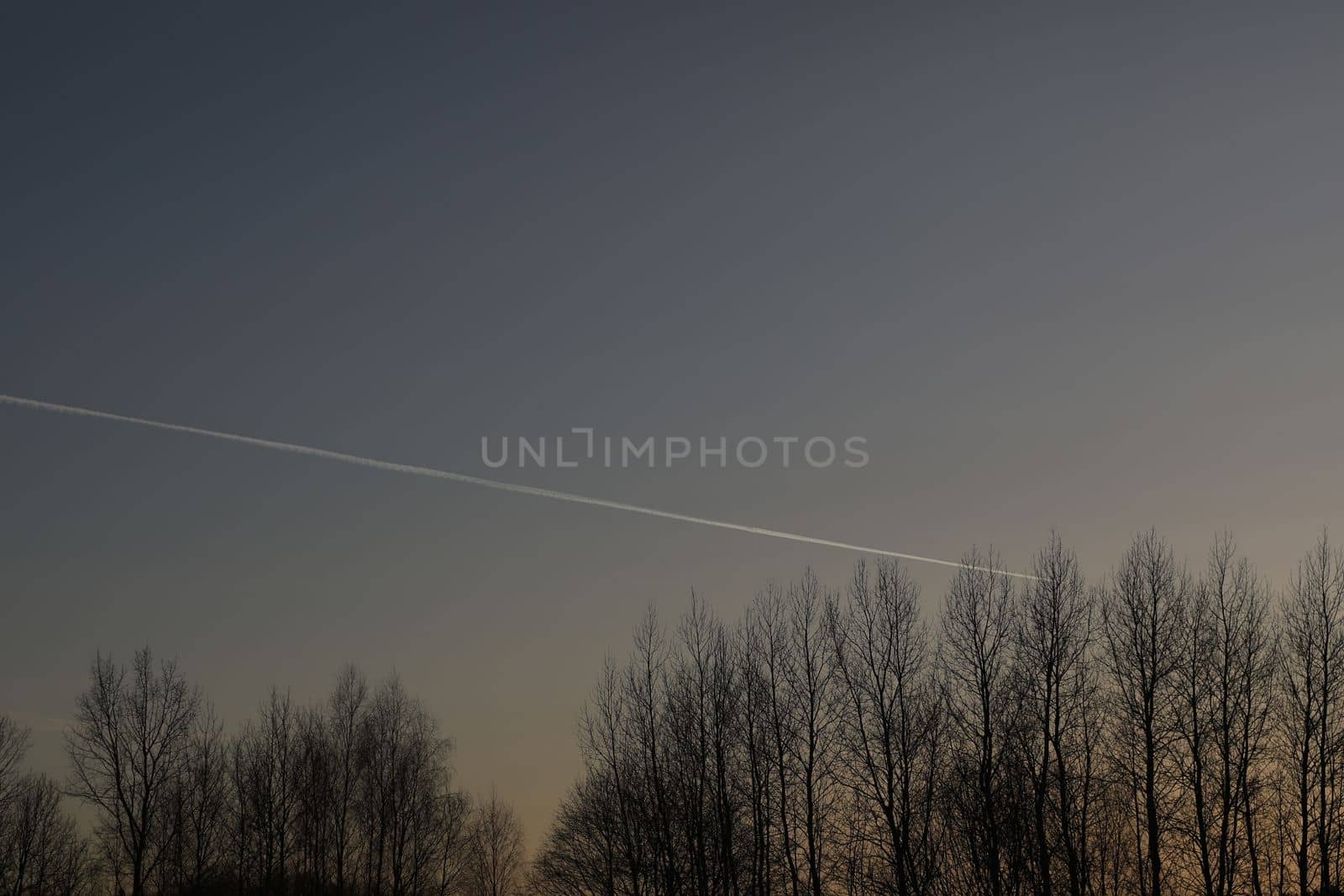 airplane flies in sunset sky and leaving trail. Amazing panoramic sunrise or sunset sky. Gradient color. Sky texture, abstract nature background