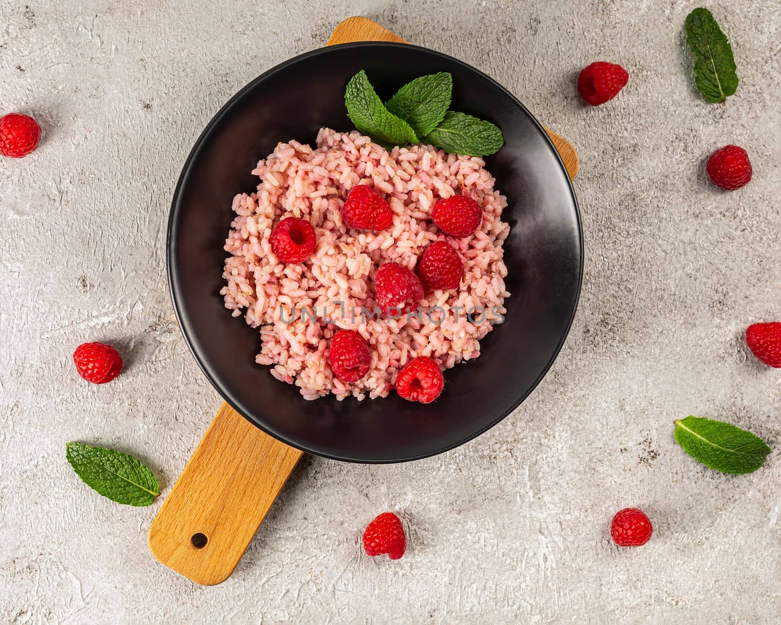 Healthy food on gray concrete background. Fresh raspberries risotto on a delicate and elegant dish