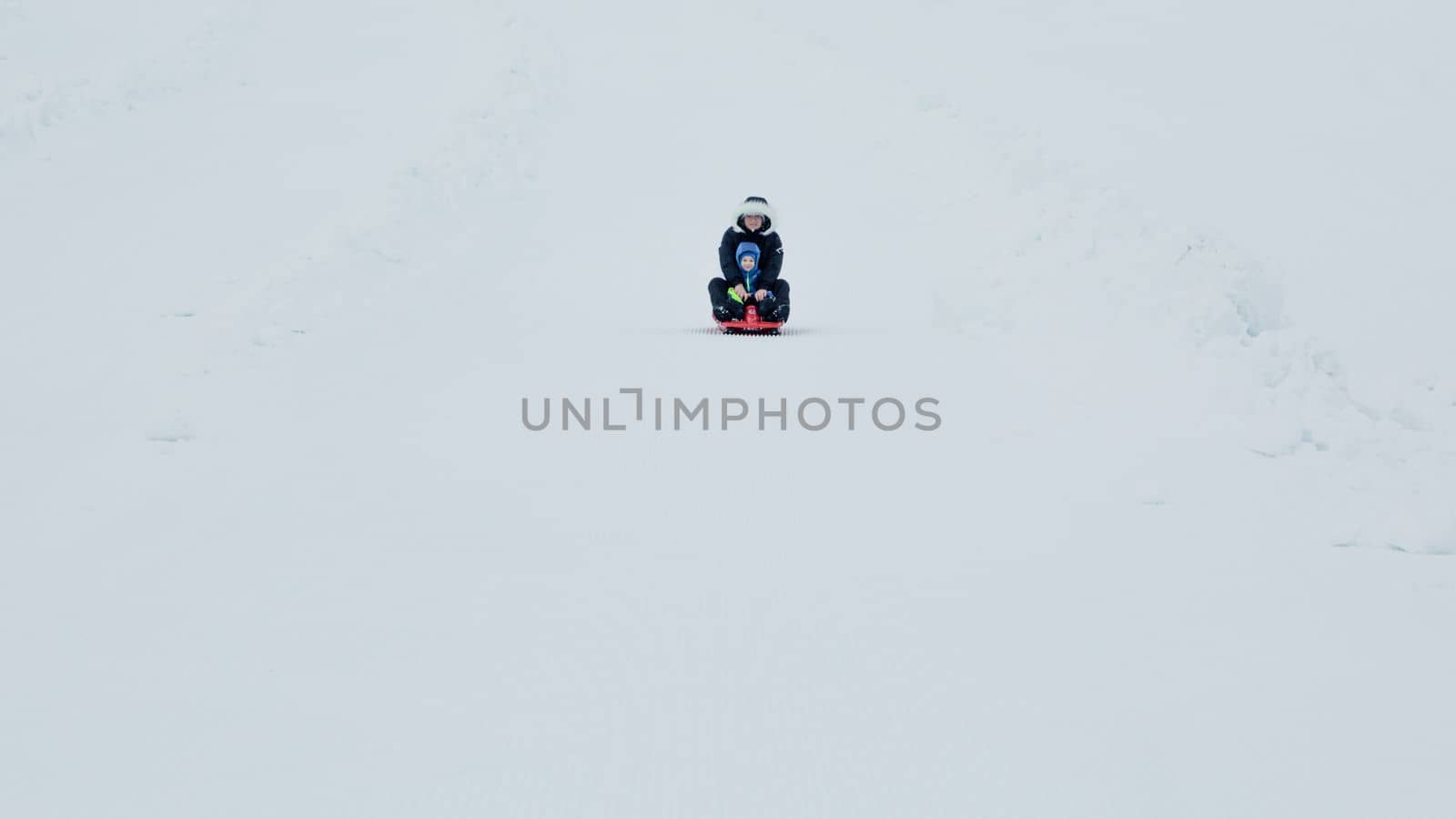 Children sled in the Alps mountains in winter. by Ciorba