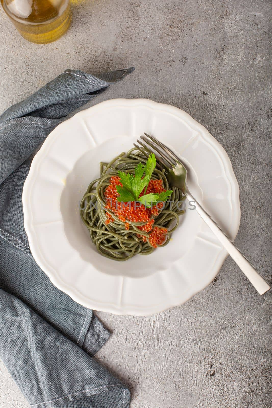 Spirulina noodles with red caviar on a white plate top view by Ciorba