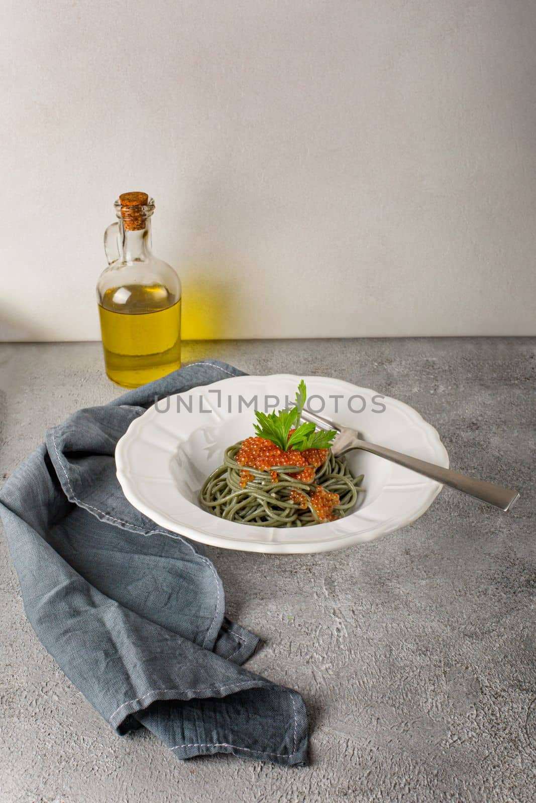 Healthy clean eating food: spirulina spaghetti with red caviar on concrete background with copy space, top view. Asian food creative concept