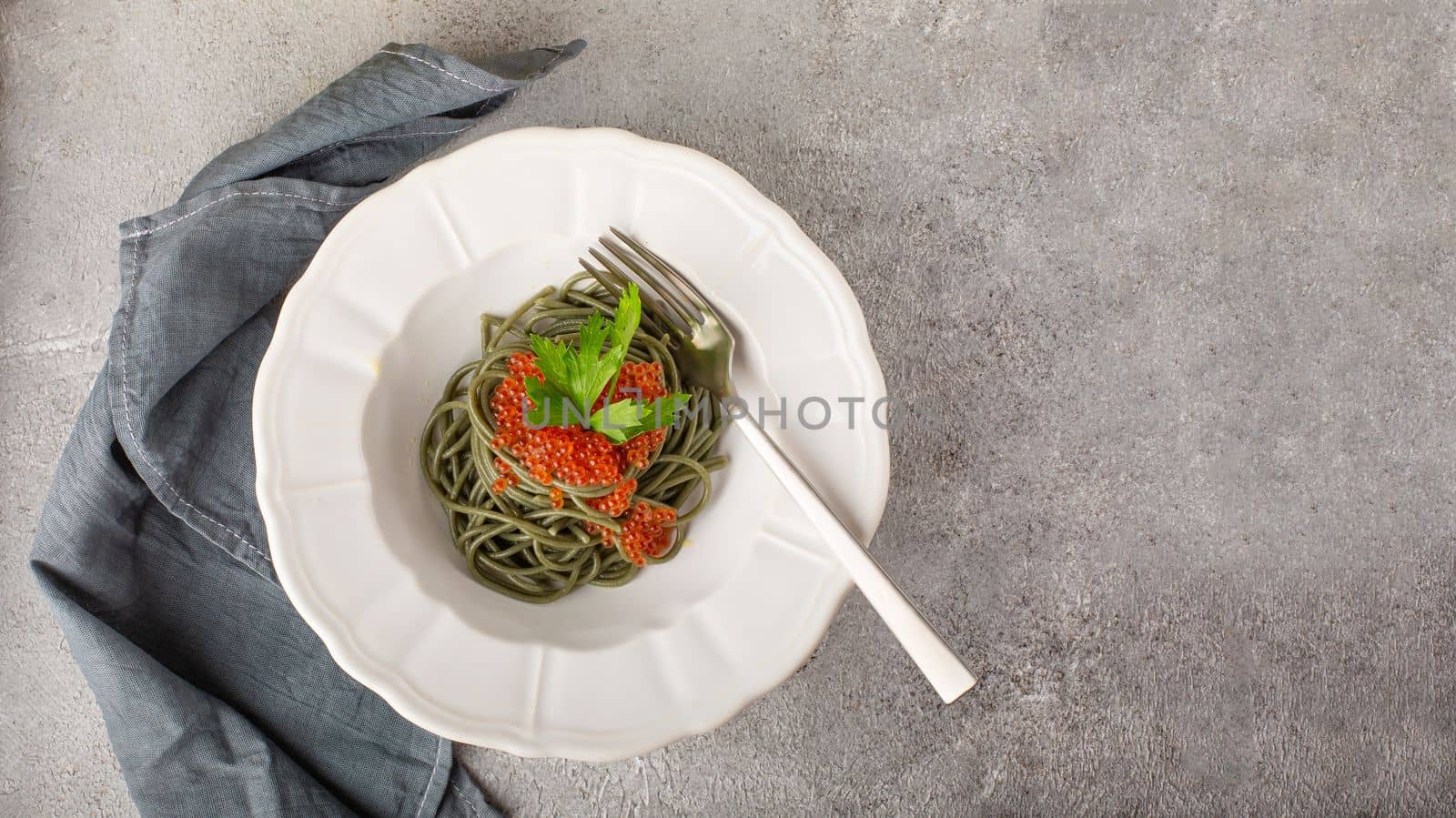 Healthy clean eating food: spirulina spaghetti with red caviar on concrete background with copy space, top view. Asian food creative concept