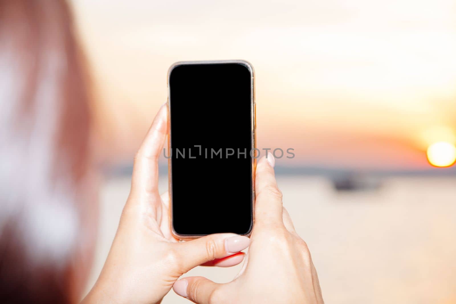 Young woman holding smart phone with mockup black blank display, empty screen for social media app ads at home. Mobile applications technology concept.