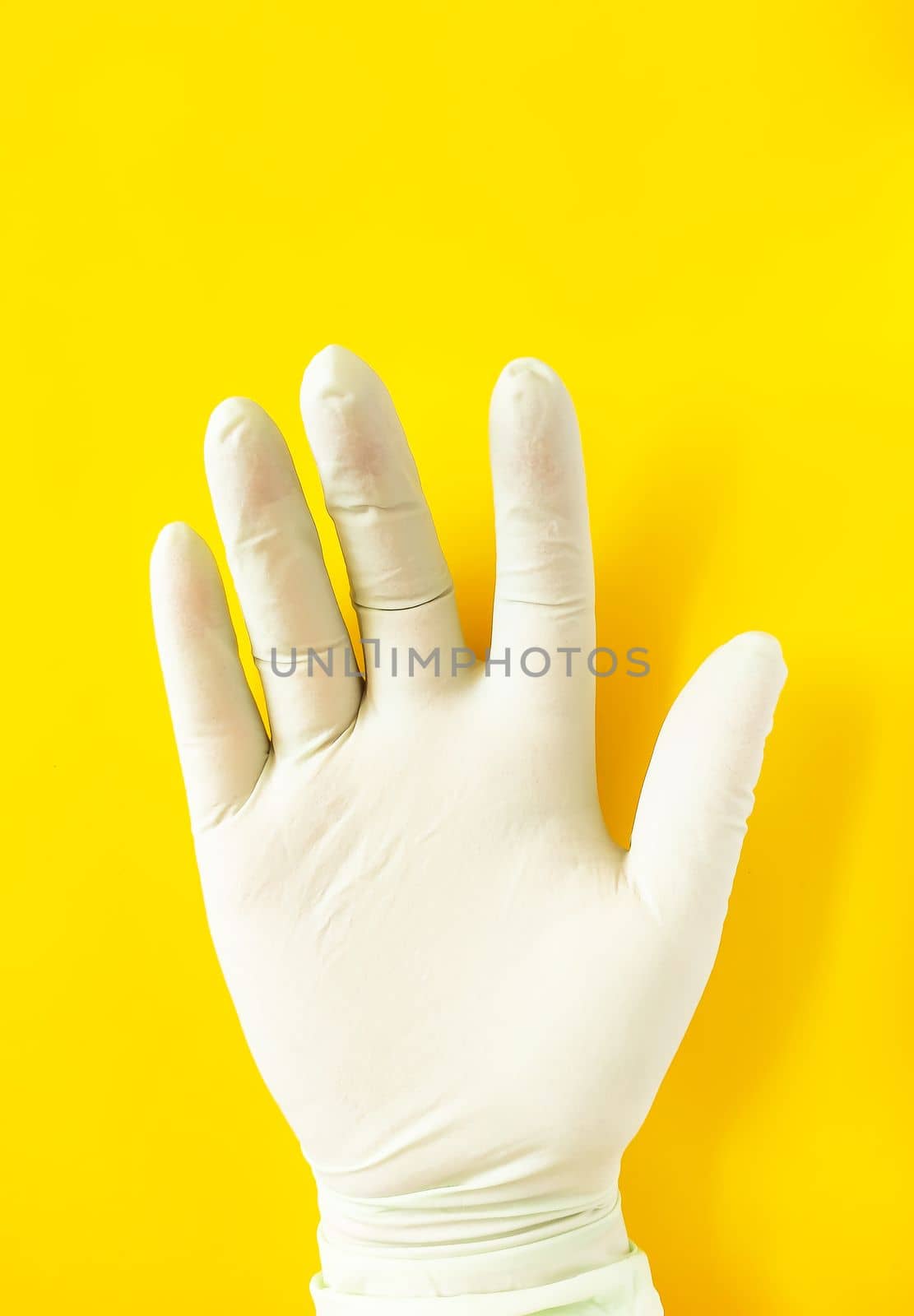 A hand in rubber glove on bright yellow background