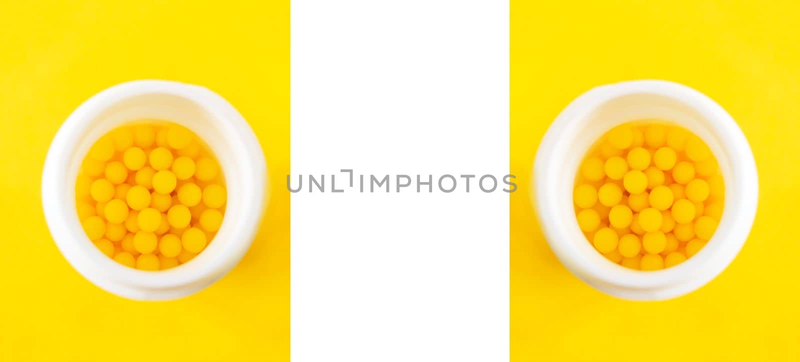 Symmetrical background with the pills of vitamin C in the opened white plastic container on bright yellow background. by nightlyviolet