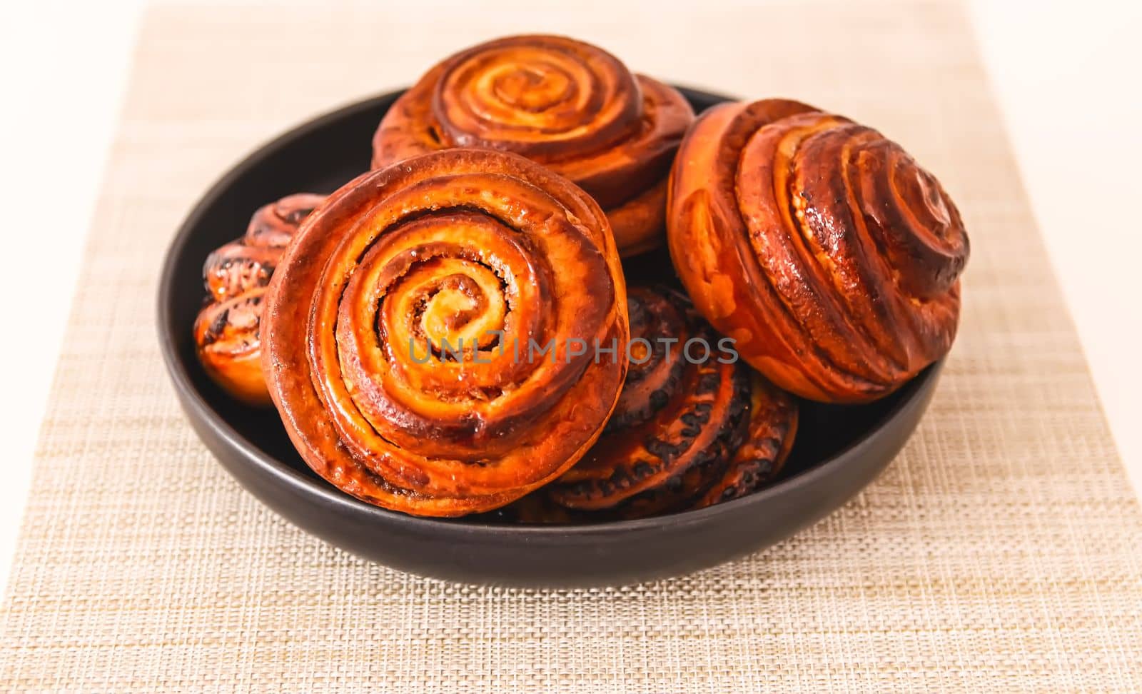 Sweet homemade cinnamon buns on a black ceramic plate.