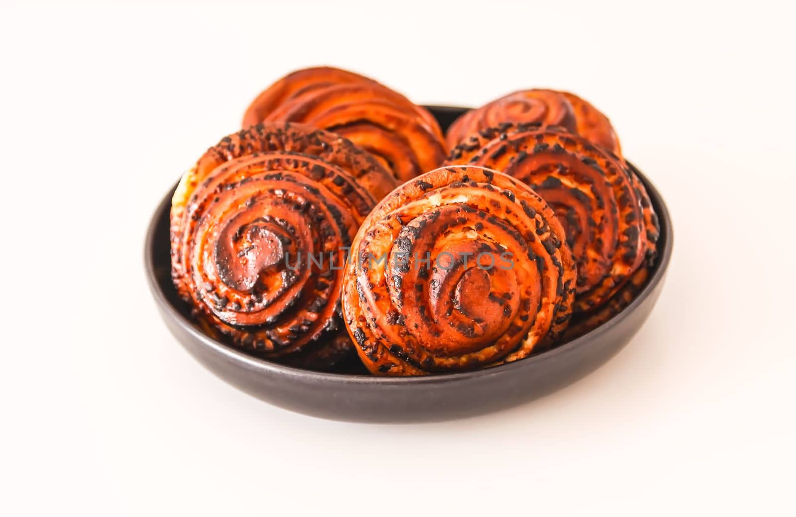 Sweet homemade cinnamon buns on a black ceramic plate.