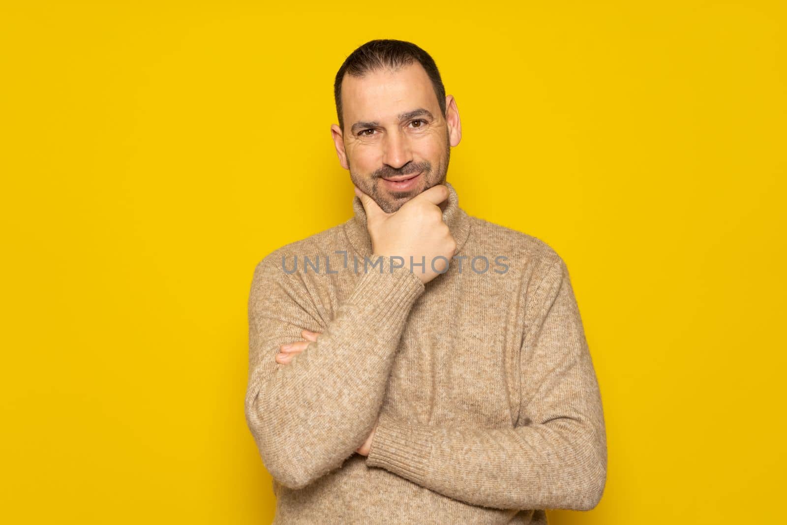 Problem solution. Bearded Hispanic man in a beige turtleneck gets rid of a problem, and. he looks up, makes up an idea. isolated yellow background