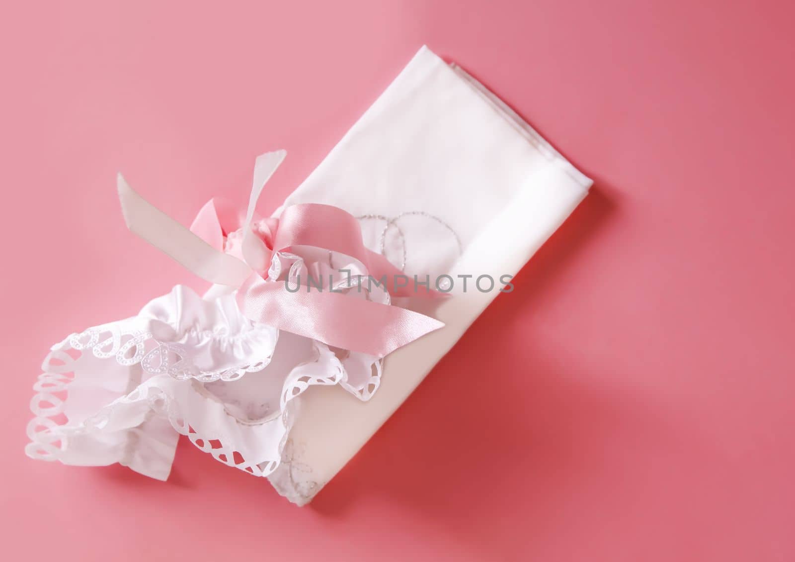 The bride's garter on a pink background. Wedding dress detail.