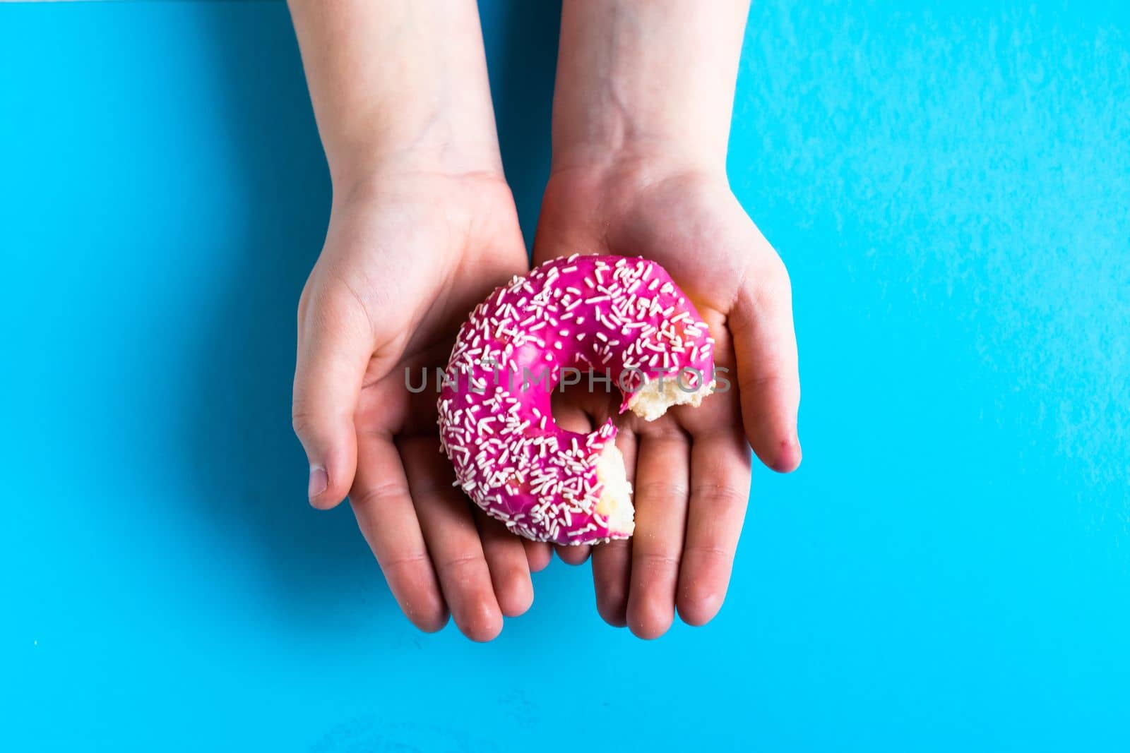 Hand holding a half eaten sweet pink donut isolated. Half eaten donut isolated. by Zelenin