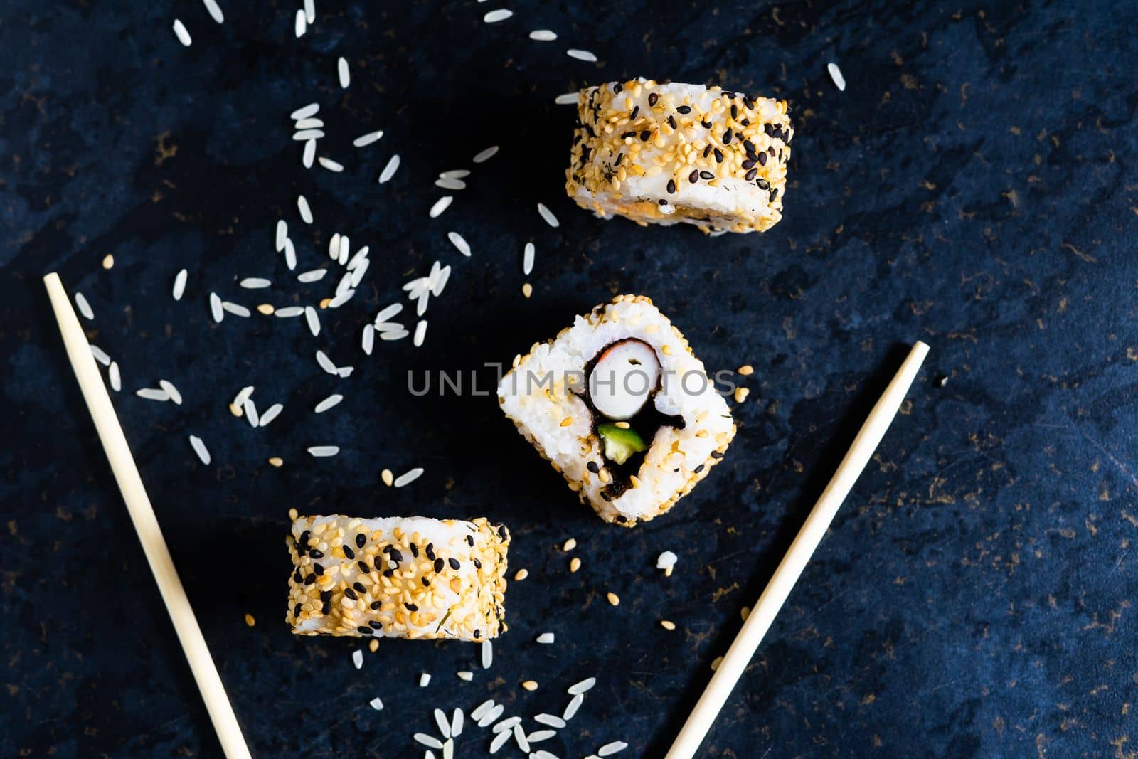 Sushi on a black table plate with wooden chopsticks. Eating japanese food at restaurant. by Zelenin