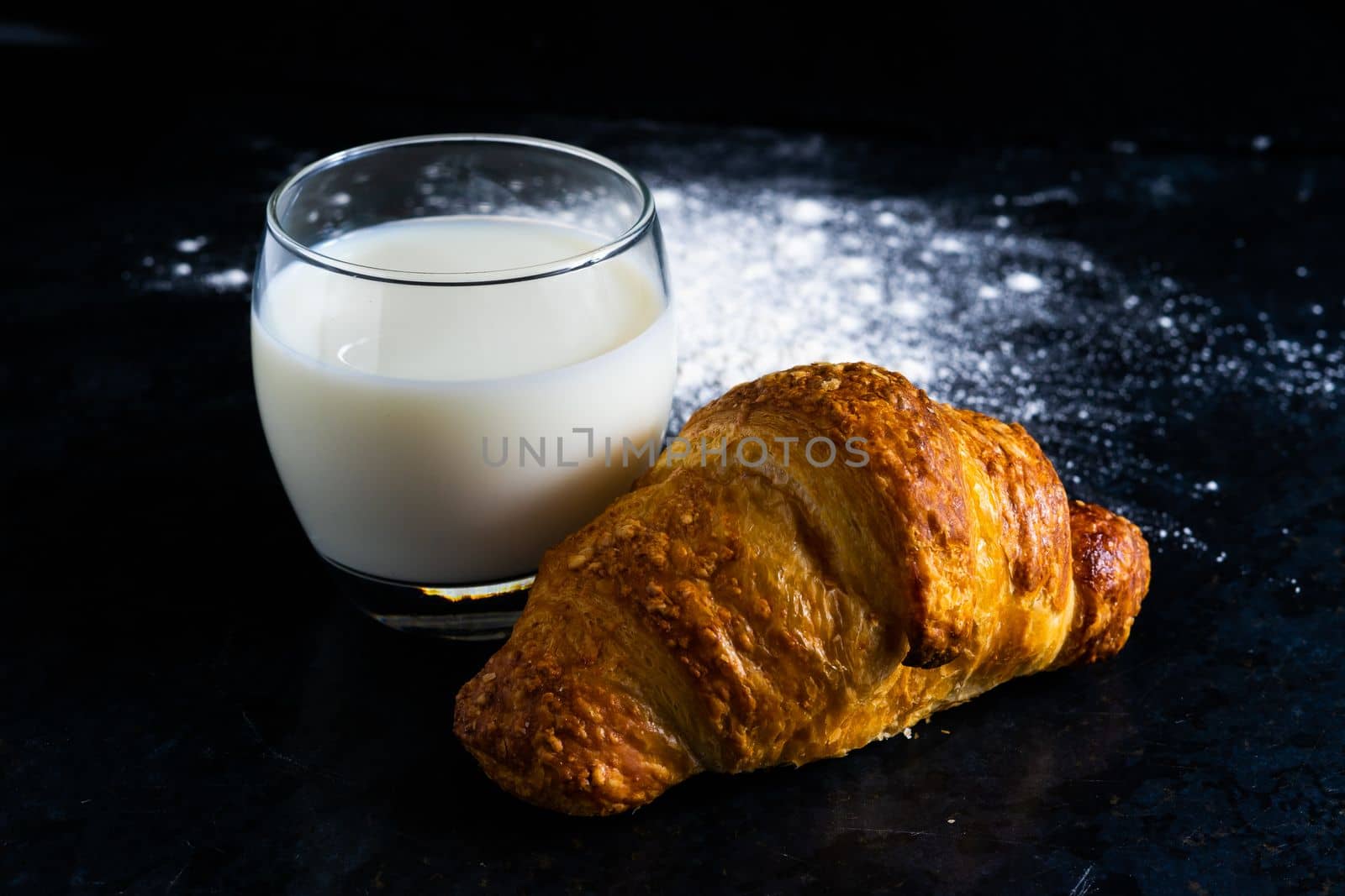 Fresh white bread and milk in white glass on black stone table background. Top view and Studio shot by Zelenin