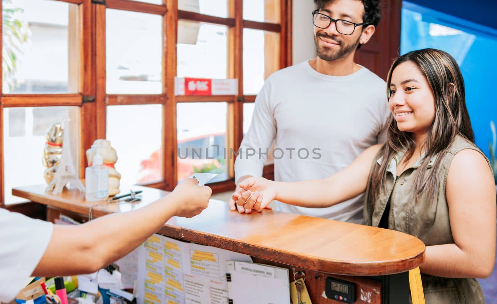Couple receiving hotel room keys. Young couple receiving card key at a hotel reception. Latin couple receiving hotel room keys. Concept of couple arriving at hotel