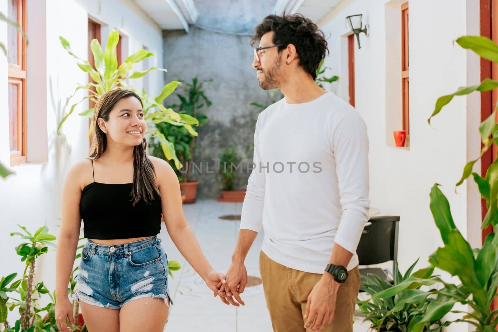 Young couple walking in corridor of tropical hotel. Smiling happy couple walking in hotel corridor.