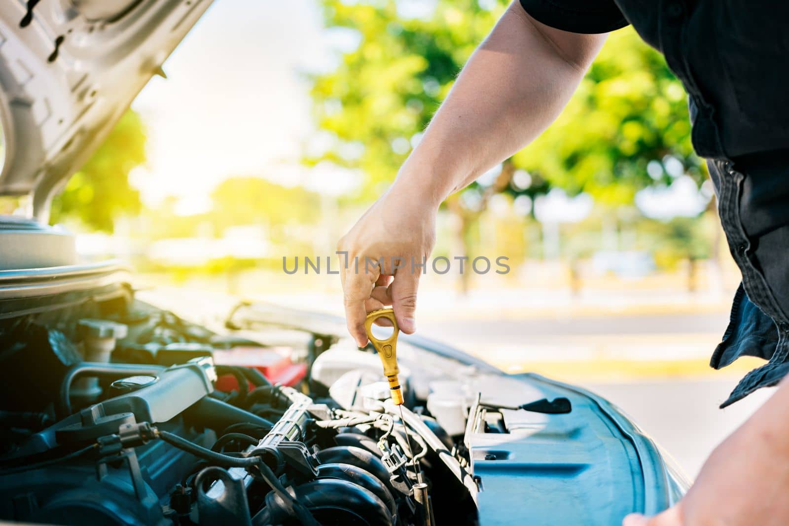 Man hand checking oil to car with copy space. People hand inspecting car oil level. Driver hand inspecting car oil level by isaiphoto