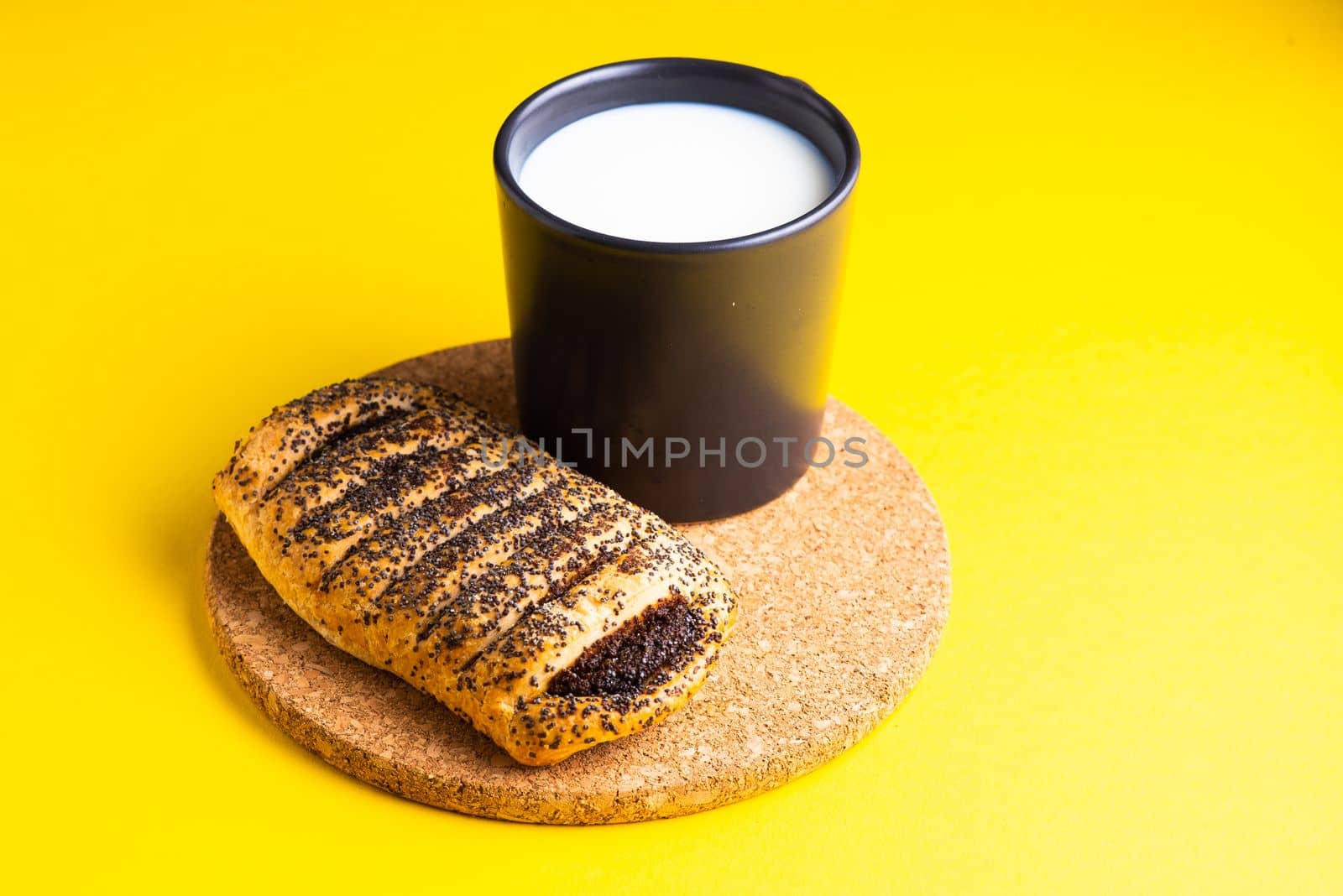 Breakfast bread and cup of milk on yellow and blue background