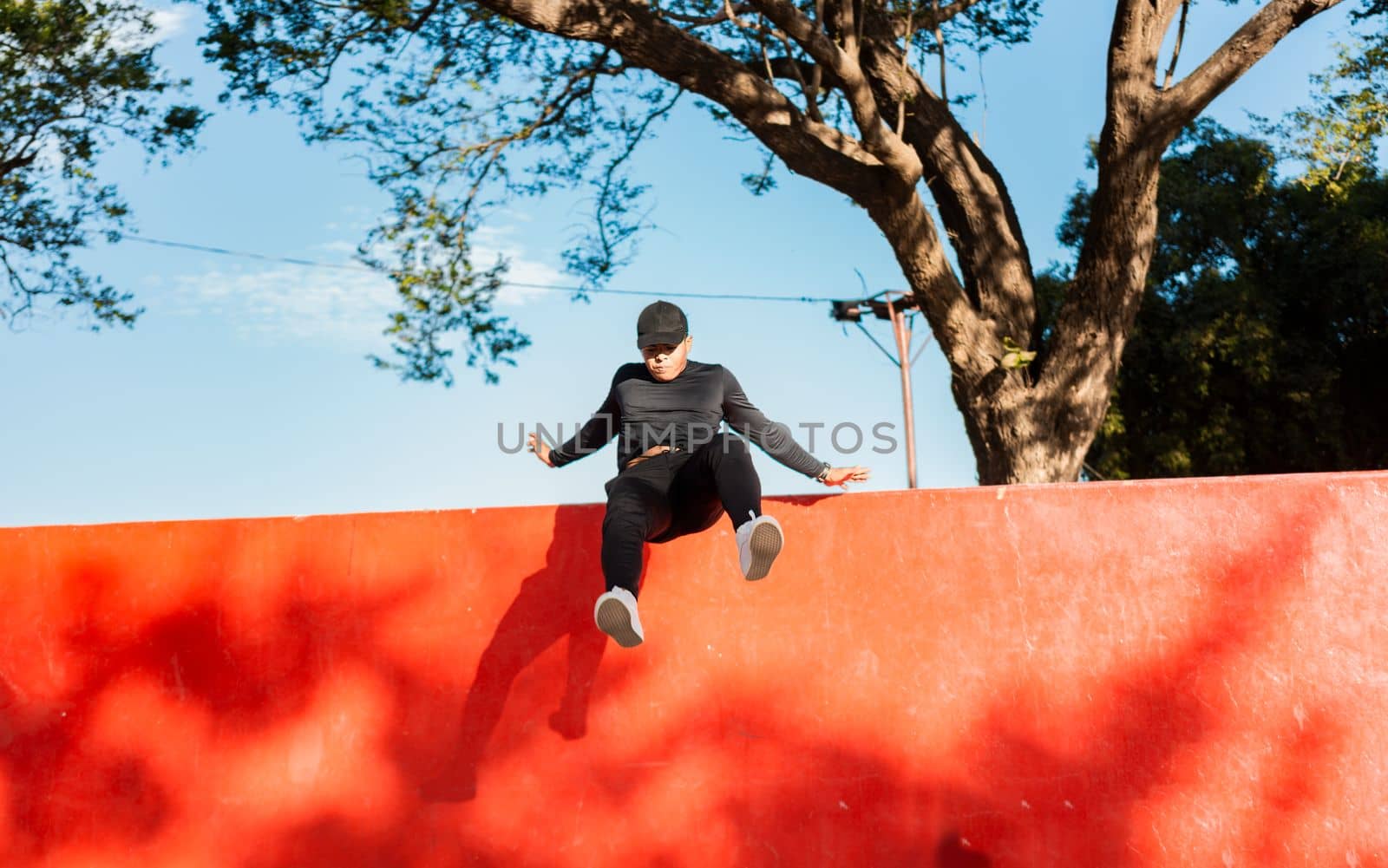 Young man doing jumping parkour at sunset. Guy doing wall jump parkour, Artistic image of man doing parkour